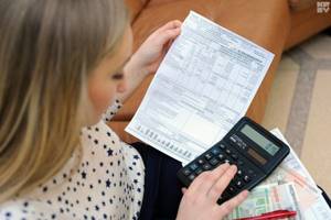 Женщина держит в руках квитанцию и калькулятор